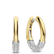 A pair of gold huggie hoop earrings with pavé-set clear stones at the bottom, shown on a clean white background.