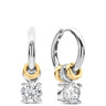 A pair of small hoop earrings with a dangling solitaire diamond and gold and white gold accents, shown on a plain white background.