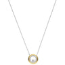 A delicate silver chain necklace featuring a circular pendant with a polished gold outer ring, a smaller inner ring paved with clear stones, and a central clear gemstone, shown against a plain white background.