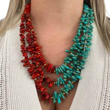 Red and turquoise beaded necklaces worn by a person against a white background