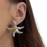 Starfish-shaped earring worn by a person with brown hair.