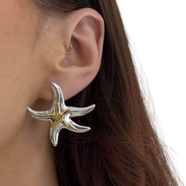 Starfish-shaped earring worn by a person with brown hair.