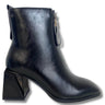 A black faux-leather ankle boot with a chunky geometric block heel, a pointed toe, and a side zipper with a decorative pull tab, shown against a plain white background.