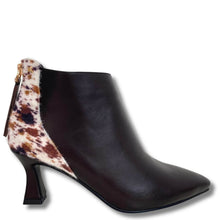 A dark brown leather ankle boot with a pointed toe and a chunky block heel, featuring a contrasting cowhide-patterned insole and a gold-tone zipper pull on the side.