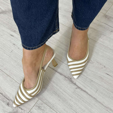 Striped shoes worn with blue jeans on a light wooden floor