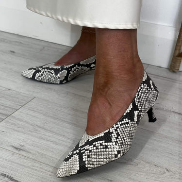 Black and white snake print high heels on a light wooden floor.