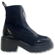A black ankle boot with a chunky platform sole, featuring a mix of matte suede and glossy patent leather panels, shown against a plain white background.