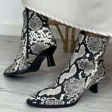 Black and white patterned high-heeled shoes on a light wooden floor.