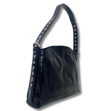 A patent black leather shoulder bag with a wide strap adorned with silver-tone metal studs, shown against a plain white background.