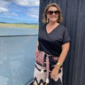 Woman standing outdoors with a scenic view of water and sky in the background