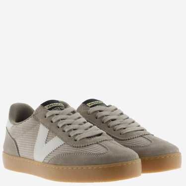 Pair of taupe sneakers with a white logo on a light gray background