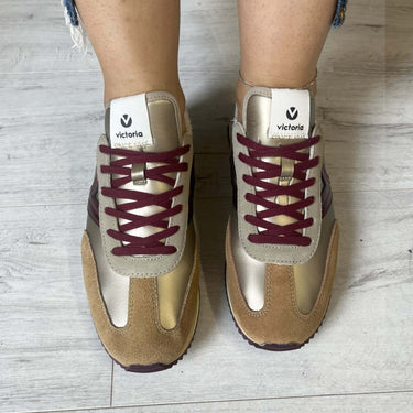 Beige and maroon sneakers with 'Victoria' branding on a light wooden floor.