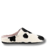 A single plush slip-on mule slipper with a black and white cow-print pattern, featuring a soft pink lining and a small white brand tag on the side.