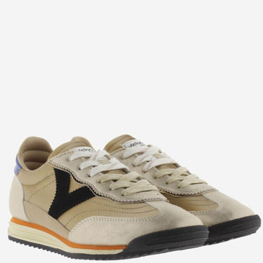 Pair of beige sneakers with black and orange accents on a white background