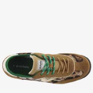 Brown sneaker with green laces and a patterned sole on a white background