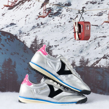 Silver sneakers with pink and black accents on a snowy mountain background