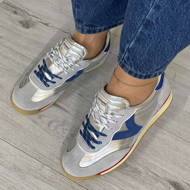 Person wearing blue and white sneakers on a wooden floor