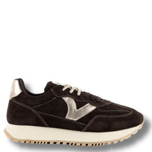 A dark brown suede sneaker with a metallic silver chevron logo on the side, black laces, and a thick cream midsole with a gum outsole, shown against a plain white background.