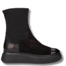 A black ankle boot with a textured leather cap toe, elastic side gore, and a chunky ridged platform sole, shown from a side profile on a white background.