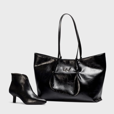 Black leather handbag and black ankle boot on a light gray background