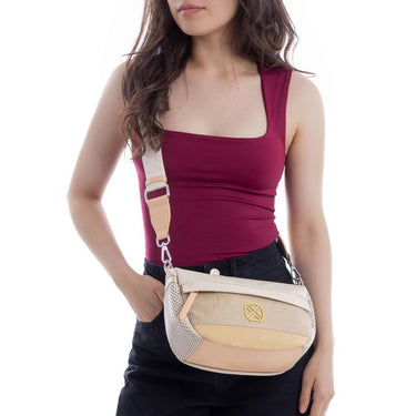 Woman wearing a beige crossbody bag on a white background