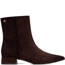 A dark brown suede ankle boot with a pointed toe and a small gold-tone circular logo stud on the side, shown against a plain white background.