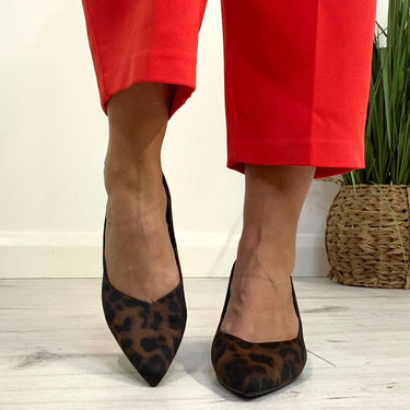 Person wearing red pants and leopard print shoes on a light wooden floor.