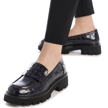 navy crocodile-patterned loafers worn with black pants on a white background