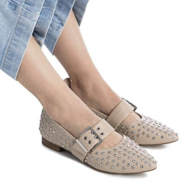 Person wearing light blue jeans and beige flat shoes on a white background