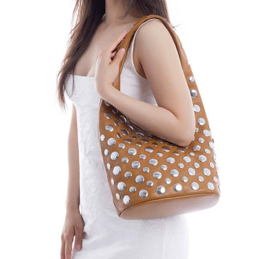 Woman holding a brown handbag with silver studs on a white background